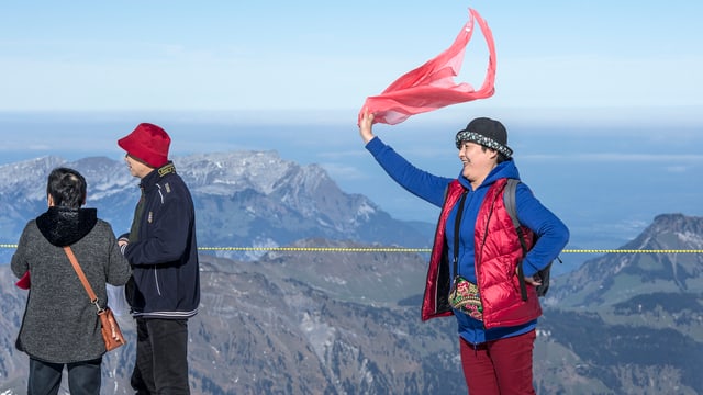 Eine chinesische Touristen schwing ein rotes Tuch auf dem Gipfel des Titlis. Eine chinesische Touristen schwing ein rotes Tuch auf dem Gipfel des Titlis.
