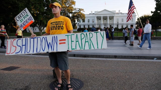 Ein Mann hält ein Schild: US-Shutdown = Tea Party