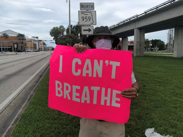 Mann mit Schild "Ich kann nicht atmen"