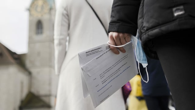 Eine Frau hält zwei Abstimmungscouverts in der Hand.