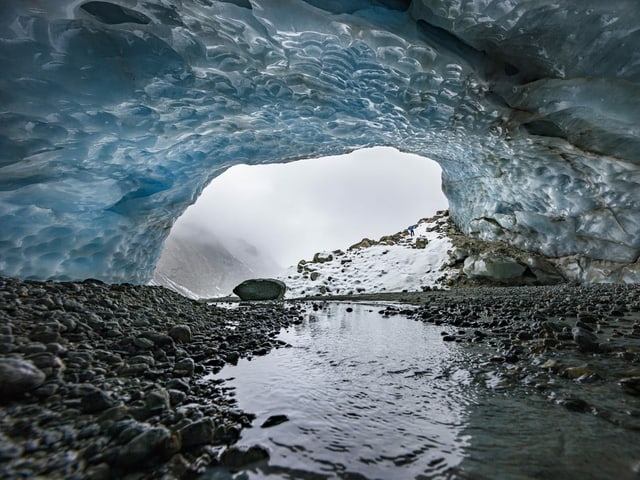 Gletscherhöhle, blau schimmernd, schneebedeckt.