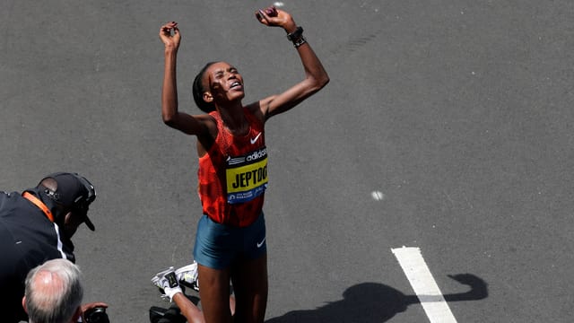 Die Kenianerin Rito Jeptoo auf den Knien mit erhobenen Händen nach dem Sieg beim Boston-Marathon 2014 Die Kenianerin Rito Jeptoo auf den Knien mit erhobenen Händen nach dem Sieg beim Boston-Marathon 2014
