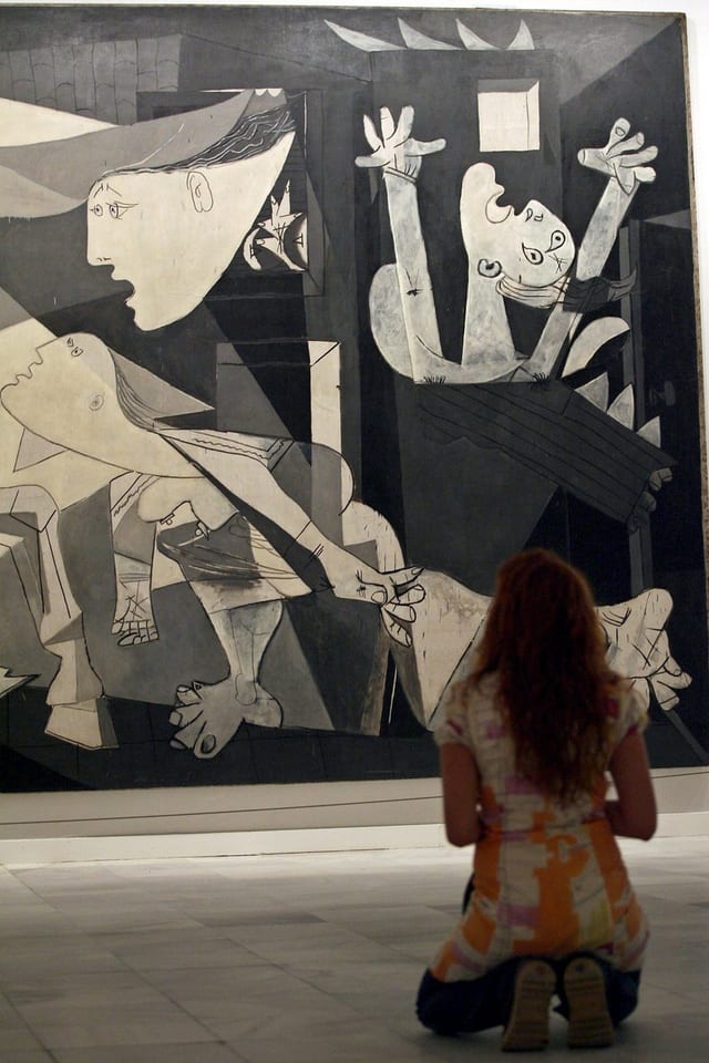 Eine Frau kniet vor Picassos «Guernica». Eine Frau kniet vor Picassos «Guernica».