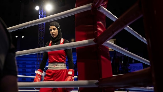 Eine Frau mit Kopftuch steht im Boxring. Eine Frau mit Kopftuch steht im Boxring.