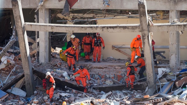 Feuerwehrleute suchen in Trümmern nach Verschütteten. Feuerwehrleute suchen in Trümmern nach Verschütteten.