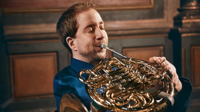 ein Mann spielt mit seinen Füssen das Horn ein Mann spielt mit seinen Füssen das Horn