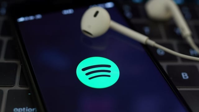 Spotify-App auf dem Handy, daneben Kopfhörer. Spotify-App auf dem Handy, daneben Kopfhörer.