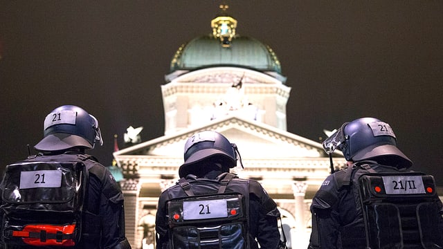 Einsatzbeamte in Kampfmontur stehen auf dieser Nachtaufnahme mit dem Rücken zur Kamera vor dem Bundeshaus in Bern. Einsatzbeamte in Kampfmontur stehen auf dieser Nachtaufnahme mit dem Rücken zur Kamera vor dem Bundeshaus in Bern.