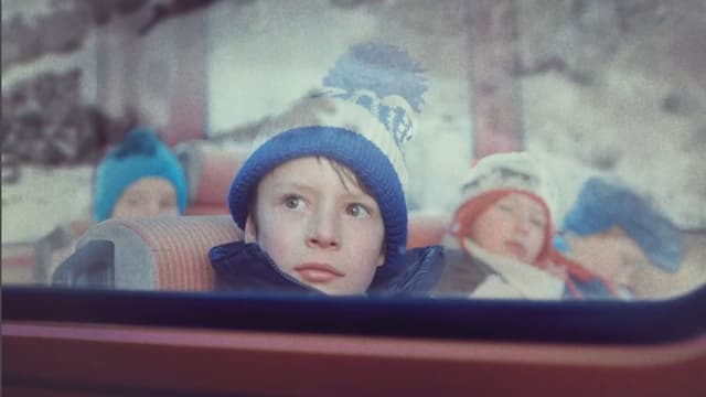 Ein Junge sitzt in einem Bus. In der FEnsterscheibe spiegelt sich ein Berg, an dem ein Bergsturz niedergeht. Ein Junge sitzt in einem Bus. In der FEnsterscheibe spiegelt sich ein Berg, an dem ein Bergsturz niedergeht.