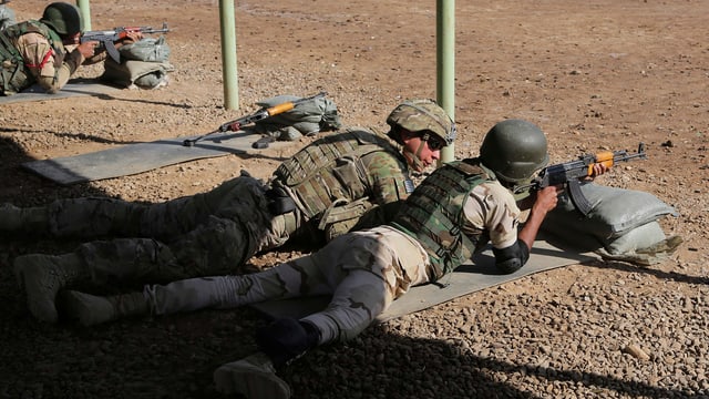 Zwei Soldaten in unterschiedlicher Kampfmontur liegen auf dem Boden, der eine zielt mit einem Gewehr, der andere schaut ihm dabei zu. Zwei Soldaten in unterschiedlicher Kampfmontur liegen auf dem Boden, der eine zielt mit einem Gewehr, der andere schaut ihm dabei zu.
