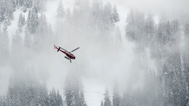 Helikopter fliegt durch den Nebel, im Hintergrund Schnee und Tannen. Helikopter fliegt durch den Nebel, im Hintergrund Schnee und Tannen.