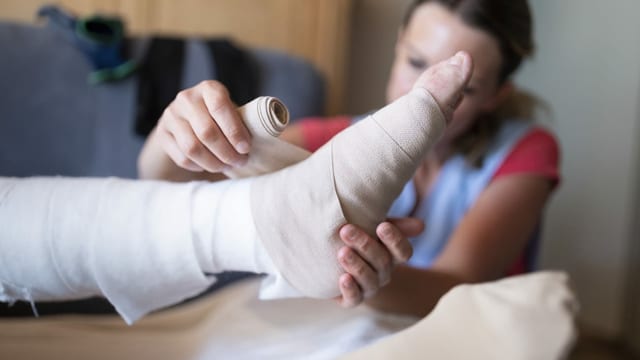 Eine Spitex-Pflegerin legt einen Verband an Eine Spitex-Pflegerin legt einen Verband an