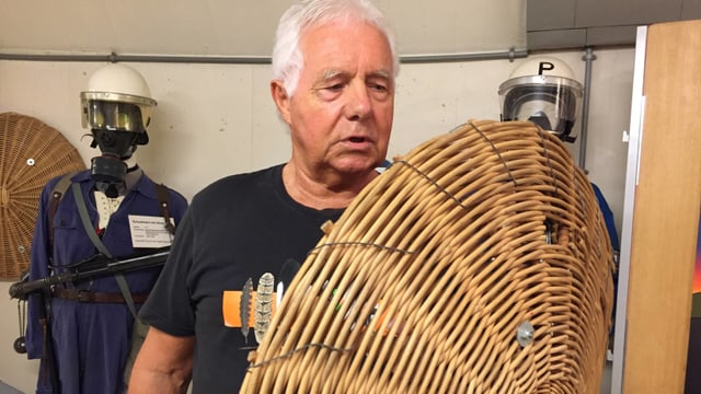Ein Mann mit weissen Haaren hält ein geflochtenes Schild in der Hand. Ein Mann mit weissen Haaren hält ein geflochtenes Schild in der Hand.