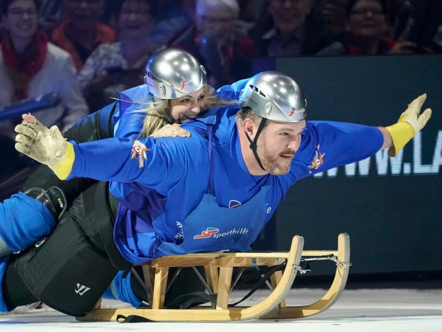 Silvana Tirinzoni und Christian Stucki liegen zu zweit auf einem Schlitten. Silvana Tirinzoni und Christian Stucki liegen zu zweit auf einem Schlitten.