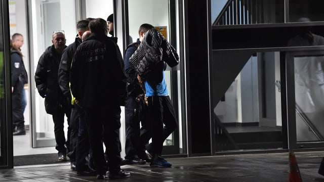 Der Angreifer wird von der Polizei abgeführt Der Angreifer wird von der Polizei abgeführt