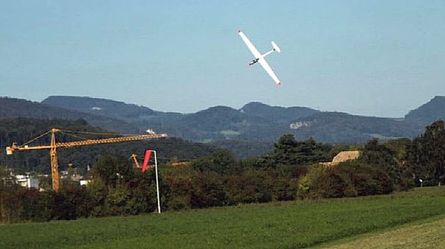 Weisses Segelflugzeug mit Nase nach unten kurz über einer Wiese. Weisses Segelflugzeug mit Nase nach unten kurz über einer Wiese.