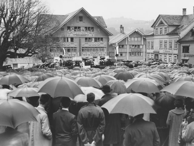 Blick auf einen Platz voller Leute, die sich mit einem Regenschirm schützen. Blick auf einen Platz voller Leute, die sich mit einem Regenschirm schützen.
