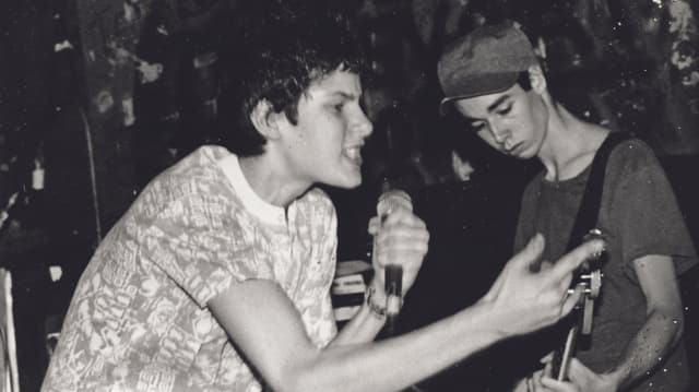 Schwarzweissfoto: Zwei junge Männer, einer mit Bass, der andere mit Mikrofon Schwarzweissfoto: Zwei junge Männer, einer mit Bass, der andere mit Mikrofon