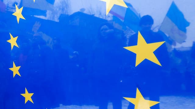 Ukrainische Demonstranten durch eine blaue EU-Flagge gesehen. Ukrainische Demonstranten durch eine blaue EU-Flagge gesehen.