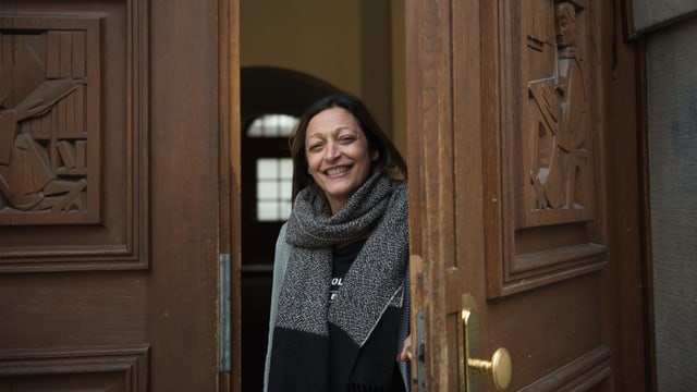 Eine Frau öffnet eine schwere Holztüre Eine Frau öffnet eine schwere Holztüre