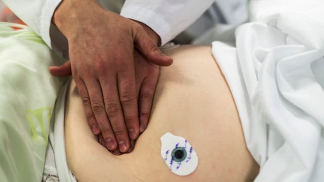 Ein Arzt tastet mit beiden Händen den Bauch eines Patienten ab. Ein Arzt tastet mit beiden Händen den Bauch eines Patienten ab.
