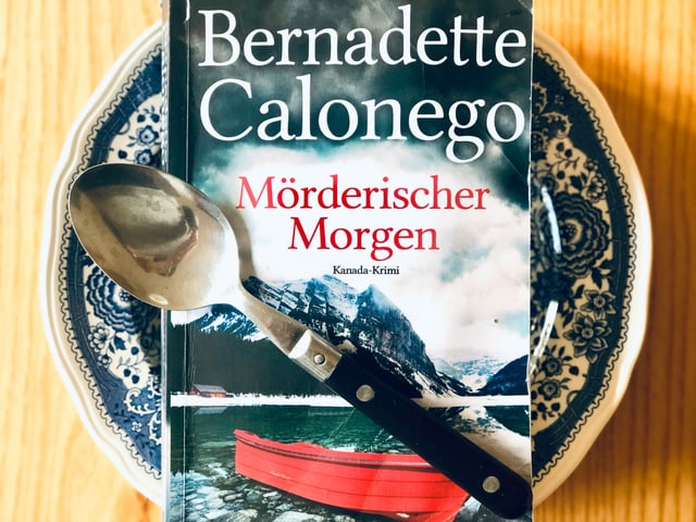 Der Krimi «Mörderischer Morgen» liegt auf einem blau gemusterten Suppenteller. Ein Esslöffel ist über das Buch gelegt. Der Krimi «Mörderischer Morgen» liegt auf einem blau gemusterten Suppenteller. Ein Esslöffel ist über das Buch gelegt.