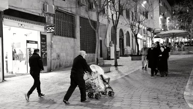 Ein älterer Mann schiebt einen Kinderwagen mit Säcken voller Flaschen durch die Fussgängerzone in Jerusalem Ein älterer Mann schiebt einen Kinderwagen mit Säcken voller Flaschen durch die Fussgängerzone in Jerusalem
