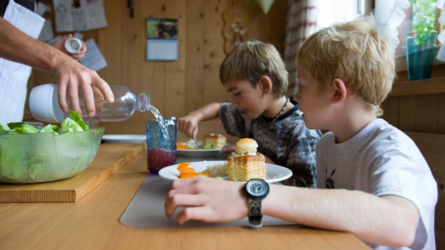 Zwei Kinder sitzen an einem Tisch und essen Pasteli. Zwei Kinder sitzen an einem Tisch und essen Pasteli.