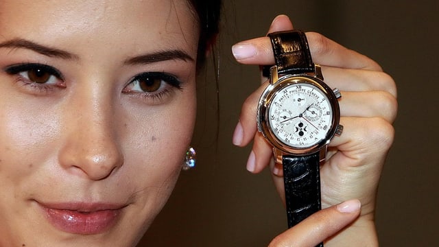 Eine junge Dame asiatischer Herkunft präsentiert eine Schweizer Uhr Eine junge Dame asiatischer Herkunft präsentiert eine Schweizer Uhr