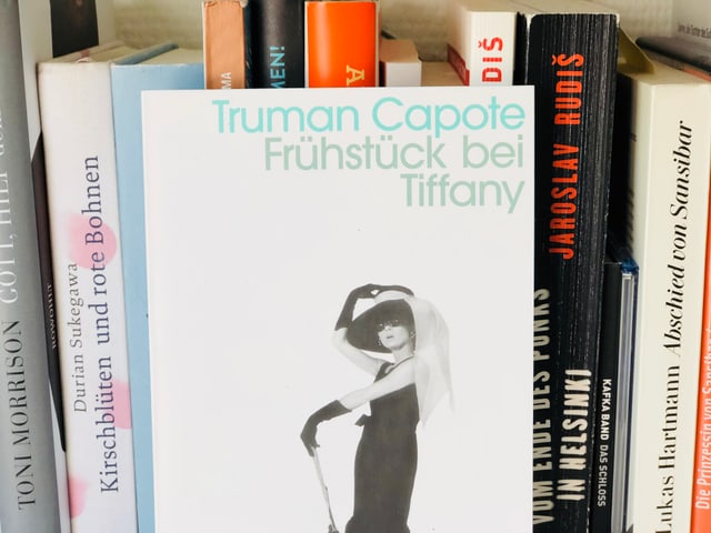 Das Buch «Frühstück bei Tiffany» von Truman Capote im Bücherregal aufgestellt Das Buch «Frühstück bei Tiffany» von Truman Capote im Bücherregal aufgestellt