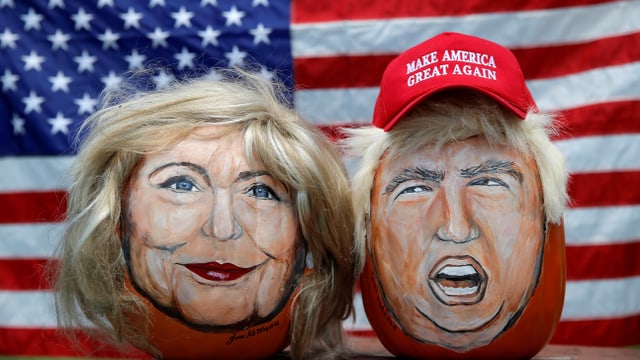 Karikaturen von Clinton und Trump vor einer US-Flagge. Karikaturen von Clinton und Trump vor einer US-Flagge.
