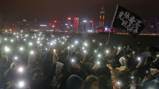 Eine Menschenmenge zündet kleine Lichter an am Flussufer in Hongkong. Eine Menschenmenge zündet kleine Lichter an am Flussufer in Hongkong.