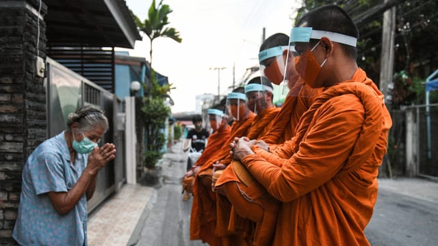 Buddhistische Mönche sammeln Almosen mit Gesichtsschutz. Buddhistische Mönche sammeln Almosen mit Gesichtsschutz.