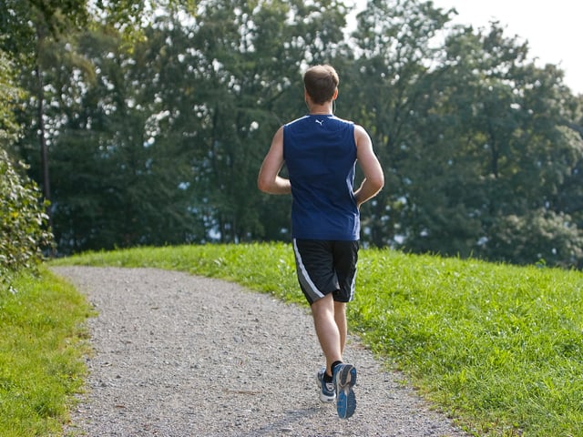 Junger Mann joggt über einen Kiesweg. Junger Mann joggt über einen Kiesweg.