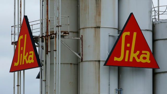 Zwei dreieckige Sika-Logo an einem grauen Stahlturm Zwei dreieckige Sika-Logo an einem grauen Stahlturm