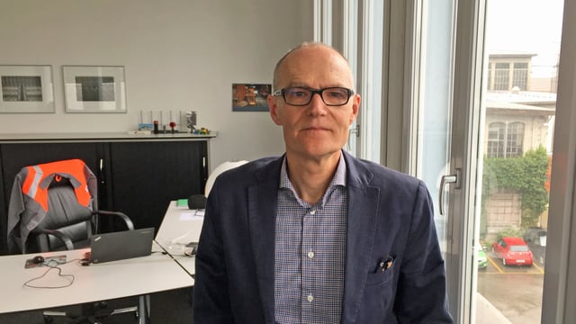 Mann im Büro, über Stuhllehne hängt eine Arbeiterjacke Mann im Büro, über Stuhllehne hängt eine Arbeiterjacke