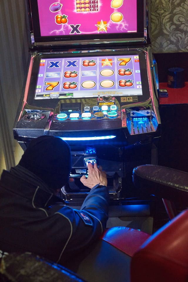 Polizist kniet vor buntem Spielautomat. Polizist kniet vor buntem Spielautomat.