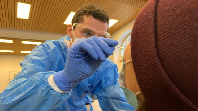 Fachperson entnimmt Probe mit einem langen Wattestäbchen Fachperson entnimmt Probe mit einem langen Wattestäbchen