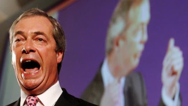 Nigel Farage spricht, sein Mund steht offen, er schwitzt, im Hintergrund eine Projektion von sich selber. Nigel Farage spricht, sein Mund steht offen, er schwitzt, im Hintergrund eine Projektion von sich selber.