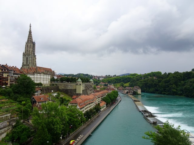 Das Bernermünster. Darunter die Aare, darüber der wolkenverhangene Himmel.