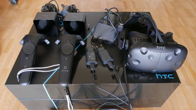 Eine Brille, zwei Sensoren, zwei Controller und einiges an Kabeln kommt aus der HTC Vive Box. Eine Brille, zwei Sensoren, zwei Controller und einiges an Kabeln kommt aus der HTC Vive Box.