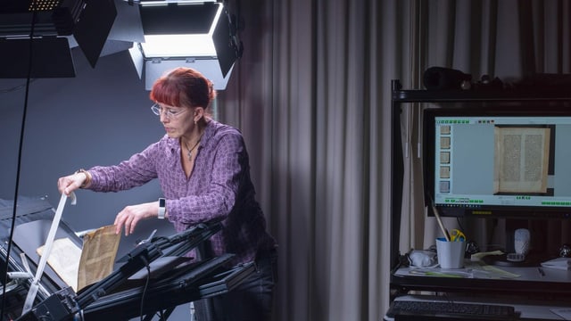 Eine Frau scannt einen alten Druck ein. Eine Frau scannt einen alten Druck ein.