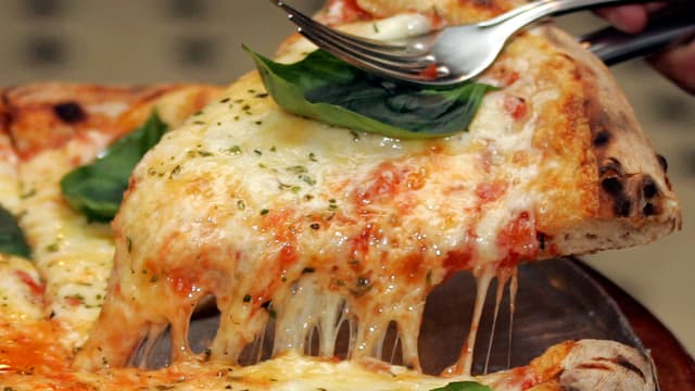 Eine Peson hebt ein Pizza-Stück vom Teller. Eine Peson hebt ein Pizza-Stück vom Teller.