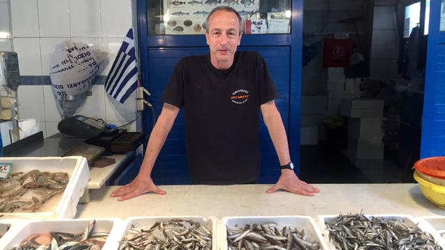 Mann vor Kisten mit kleinen Fischen drin in einem Laden. Mann vor Kisten mit kleinen Fischen drin in einem Laden.