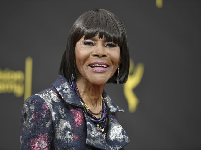 Eine afroamerikanische Frau steht vor einer Leinwand und lacht. Eine afroamerikanische Frau steht vor einer Leinwand und lacht.