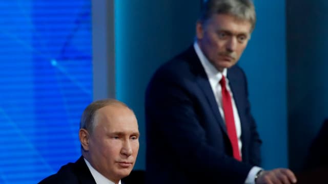 Peskov hört Putin bei einer Rede zu.