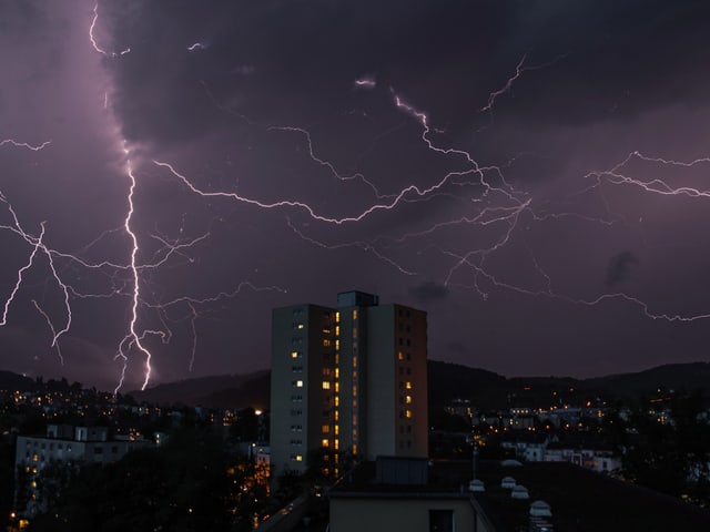Viele Blitze erhellen den Himmel über einer Stadt.
