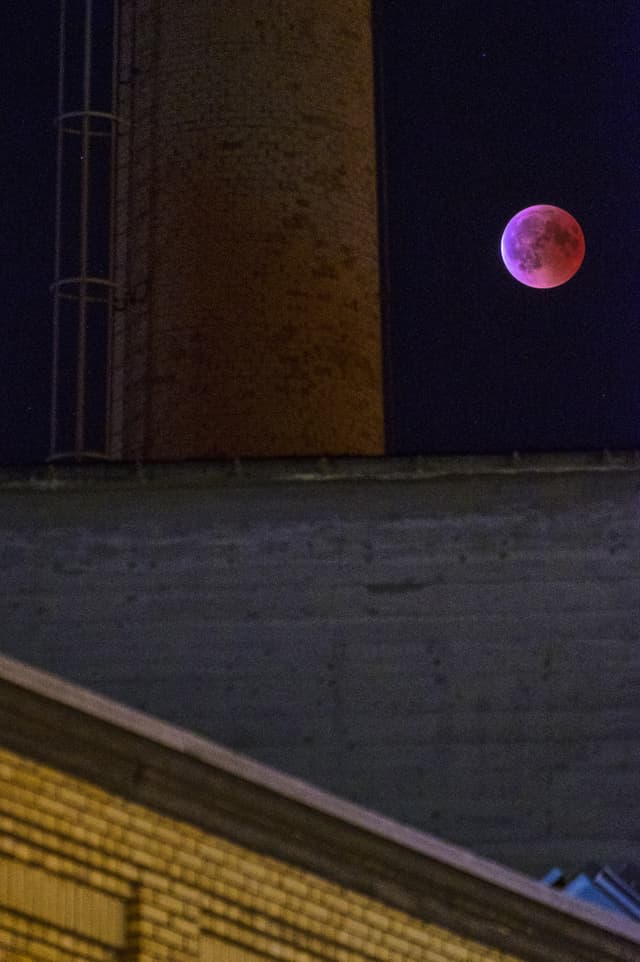 Blutmond über Örlikon/ZH. Lilafarbiger Vollmond neben Kaminturm.