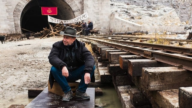 Ein Mann sitzt an einem Filmset vor einem Tunnel. Ein Mann sitzt an einem Filmset vor einem Tunnel.