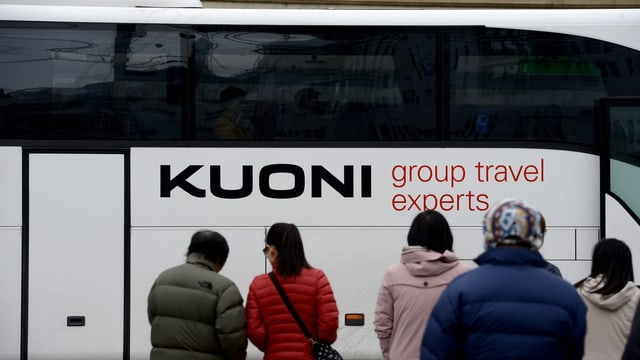 Reisebus mit Auschrift Kuoni, davor von hinten fotografiert wartende Reisende Reisebus mit Auschrift Kuoni, davor von hinten fotografiert wartende Reisende